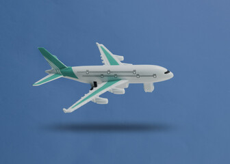 Airplane model hovering on blue background with a shadow. Travel concept