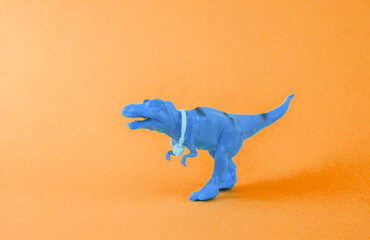Toy dinosaur tyrannosaurus rex with headphones on a orange background. Minimalism creative layout
