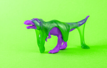 Toy dinosaur tyrannosaurus rex with slime on green background. Minimalism creative layout