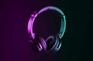 Fototapeta na wymiar Black wireless stereo headphones isolated on black background in neon light