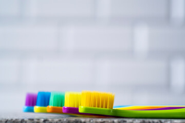 Multi-colored toothbrushes on the background of the wall in the bathroom.