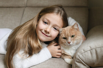 A girl near a ginger cat on the couch
