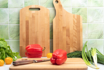 Sweet pepper pods and a kitchen knife on a cutting board.