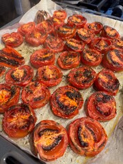 Roasted tomatoes with herbs in baking dish. Top view. Food background