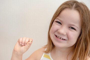 a child has lost a baby tooth, the girl holds her tooth in her hands on an isolated white background smiling