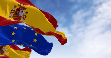 National flag of Spain waving with the European Union flag in the background on a clear day - obrazy, fototapety, plakaty