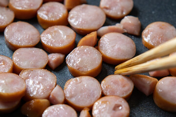 ウインナーソーセージをフライパンで炒める調理シーン。
