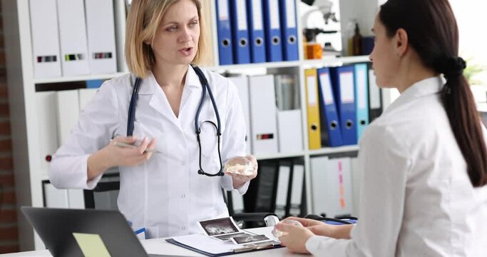 Doctor shows patient silicone breast implants to increase mammary glands. Plastic surgery concept