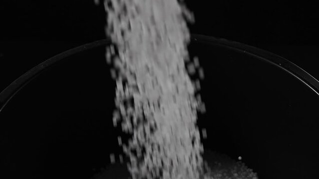 Filling the tank with plastic granules. The process of producing parts from polyethylene compound. White granules are poured into a container.
