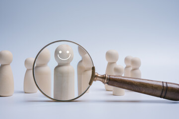 Magnifying glass focus wood doll which is among crowd for human development recruitment leadership...