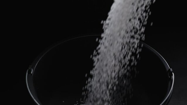 Filling the tank with plastic granules. The process of producing parts from polyethylene compound. White granules are poured into a container.