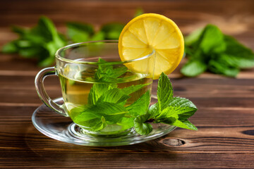 Cup of mint tea and a bunch of mint and lemon on the table