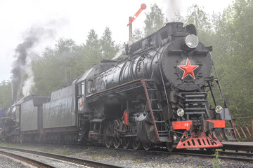 Fototapeta na wymiar View of an approaching classic steam locomotive with the Soviet emblem