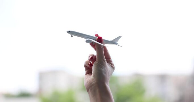 Closeup of hand holding model airplane and flights around world. Air tickets and tourism travel