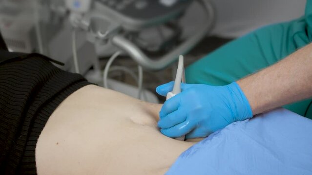 Medical Ultrasound examination. A sonographer scans a female abdomen with an ultrasound probe.
