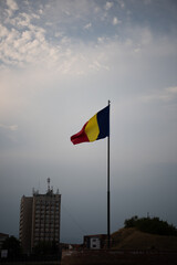 Romanian national Flag in wind in background with beautiful blue sky