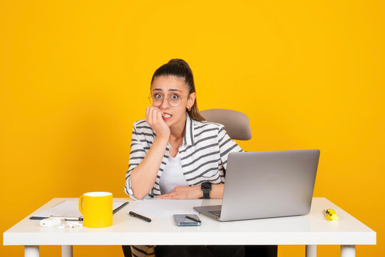 Female office worker sit at office desk wearing glasses looking afraid stressed and nervous. Businesswoman hand on mouth biting nails. Anxiety. Work on laptop. Business problems. Copy space.