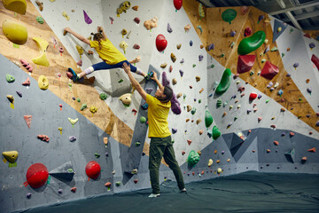 Female bouldering trainer teaching little girl, child bouldering activity, techniques. Little girl climbing wall, indoor class. Concept of sport climbing, hobby, active lifestyle, school, course © master1305