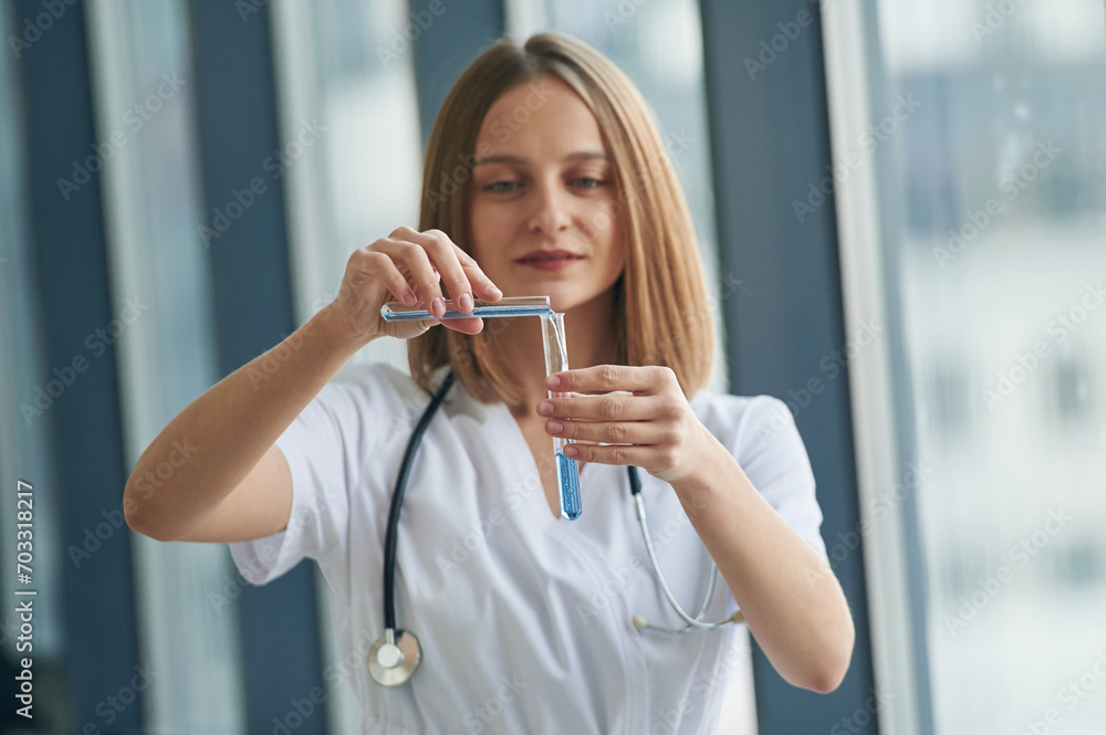 Wall mural Test tubes with liquid in them. Female doctor in white coat is in the hall