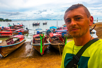 Tourist man in Ao Nang Krabi Thailand with longtail boats.