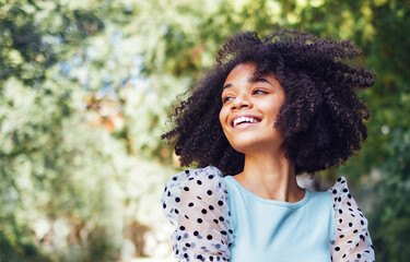 Happy african american teen girl in casual cloth. Smiling darkskin female teenager walking in the par - obrazy, fototapety, plakaty