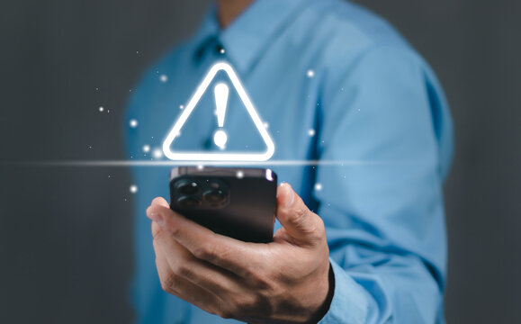 Businessman or User, programmer, developer using smart phone with triangle caution warning sign for notification error and maintenance warning and safety concept..