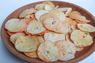 Opak is crisp made from cassava, shaped into a flat round shape. Snack from Indonesia. On a wooden plate, isolated on white background