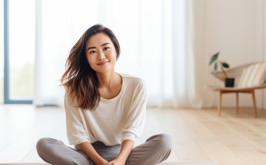Happy Smiling Asian woman sitting cross legged on the floor and smiling. Wellness and fitness concept