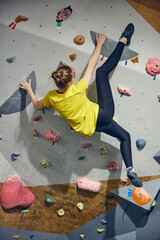 L:ittle girl, child attending bouldering course, training, climbing wall indoors. Sport education. Concept of bouldering, sport climbing, hobby, active lifestyle, school and training course