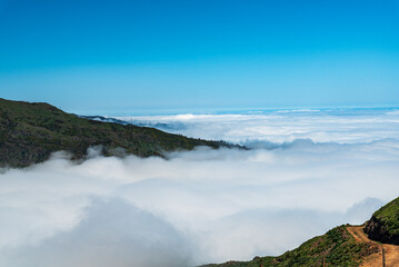 Dirt road with highest part of hill above cloudscape in Madeira - view from Levada do Paul