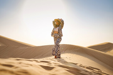 Desert adventure. Young arabian Woman in zebra suits and hat in sands dunes of UAE desert at...