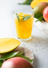 Fresh mango juice and glass with ice cubes and fresh raw fruits.