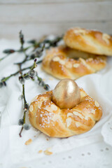 Easter buns nest shaped with golden egg on top with white natural background close up selective focus