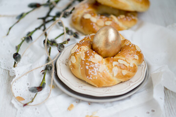Easter buns nest shaped with golden egg on top with white natural background close up selective focus