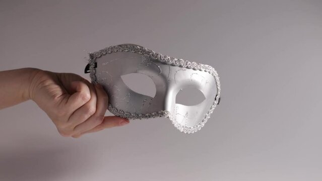 Carnival mask in hand, silver vintage masquerade accessory