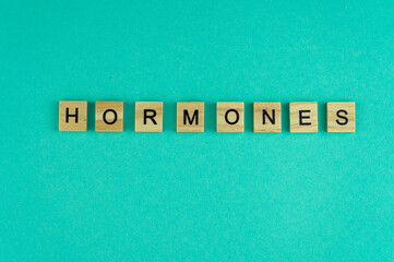 Word hormones. The phrase is laid out in wooden letters. Top view. Blue background