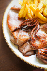 A close-up of grilled calamari with a side of fries