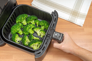 COOKING BROCCOLI FLORETS IN AIR FRYER. VEGAN FOOD RECIPES AND KETO DIET. TOP VIEW.