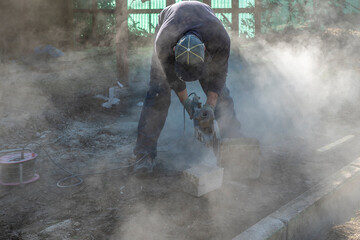 A man cuts a stone with an angle grinder - obrazy, fototapety, plakaty
