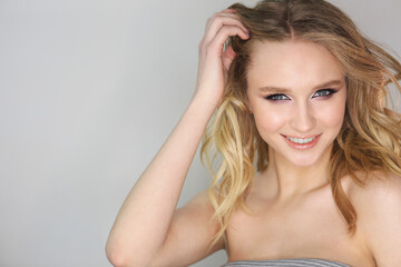 Obraz premium Young beautiful woman with blonde curly hair on grey background