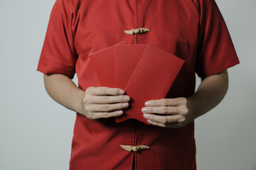 Hand of men wearing Cheongsam or Chinese traditional cloth are holding angpao or red monetary gift...
