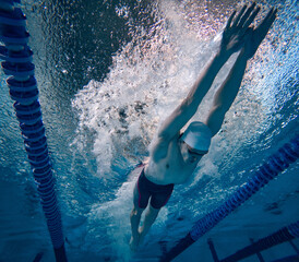 Speed and endurance. Young man, professional swimming athlete in motion, training, swimming in...