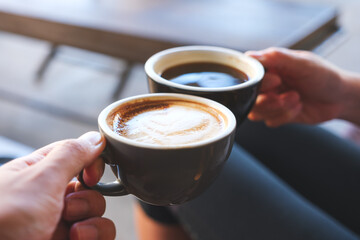 Closeup image of a couple people clinking coffee mugs in cafe
