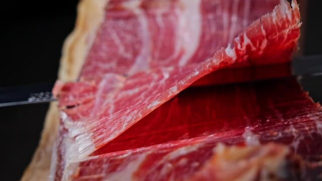 Cutting slicing a traditional Iberico Spanish ham, jamon. Whole leg. Close up