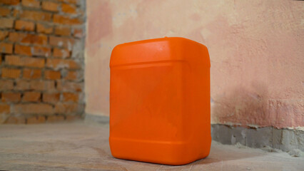 Canisters with primer on a construction site. A bright orange container for paint or primer. Orange...