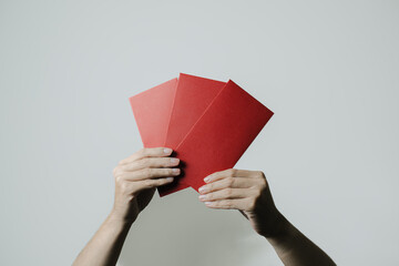 Hands holds angpao or red monetary gift on white background. Chinese New Year concept. Gong Xi Fa...