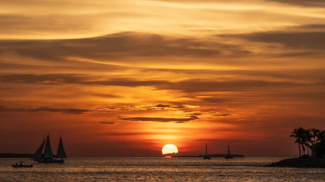 A spectacular sunset, off the coast of Key West, Florida, with sailing boats silhoutted against the orange sky