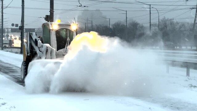 Snow removal by snow plow machine, slow motion close up. Machinery cleaning snow from the sidewalk after blizzard storm