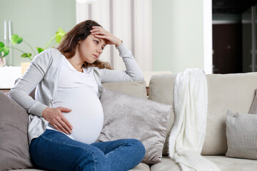 Young woman suffering from nausea and headache during pregnancy