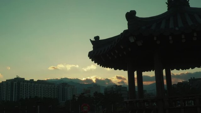 Silhouette of Korean Hanok-Style Pavilion Against Sunset Sky Over City